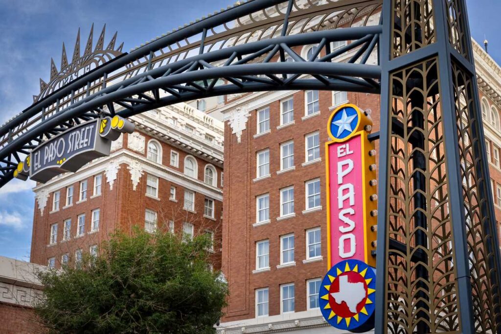 El Paso Street arch in downtown El Paso, TX, with historic buildings and an El Paso sign.